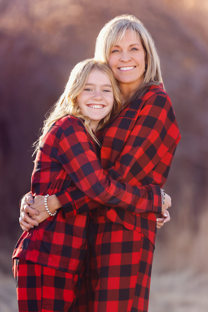 Mom hugs her daughter in matching red pajamas as they pose for a family photo with Yvonne Min.