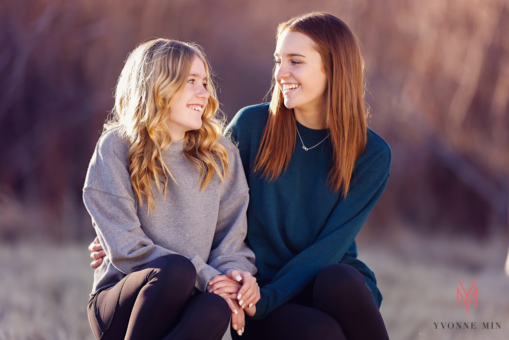 Two sisters look at each other during a family photoshoot in Thornton, Colorado.