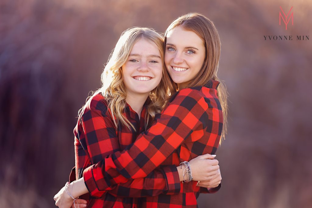 Two sisters hug each other at their family photoshoot with Yvonne Min Photography in Thornton, Colorado.