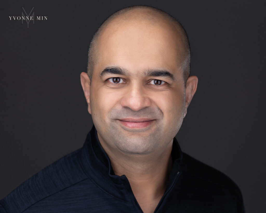 Professional headshot of a man on a dark gray backdrop by Yvonne Min Photography.