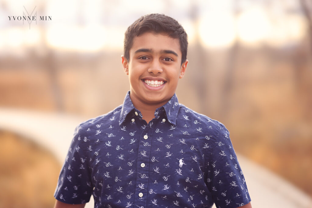 A young teenage boy smiles at the camera during his family photography session.