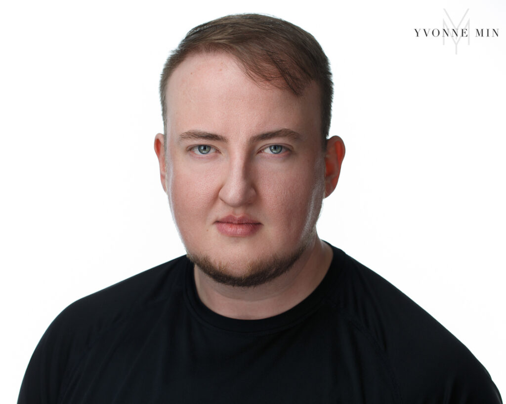 A new headshot of a male actor with a black shirt and a white backdrop taken in the studio of Yvonne Min Photography in Thornton, Colorado.