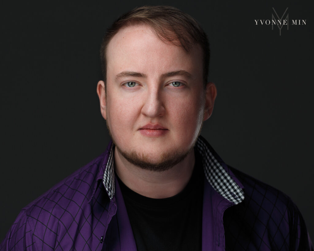 A new headshot of a man in a purple shirt with a dark background that will be used for a play in Denver, Colorado.