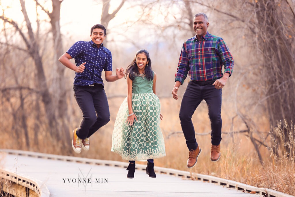 A dad, son and daughter jump at the same time for a camera during their family photoshoot session with Yvonne Min Photography.