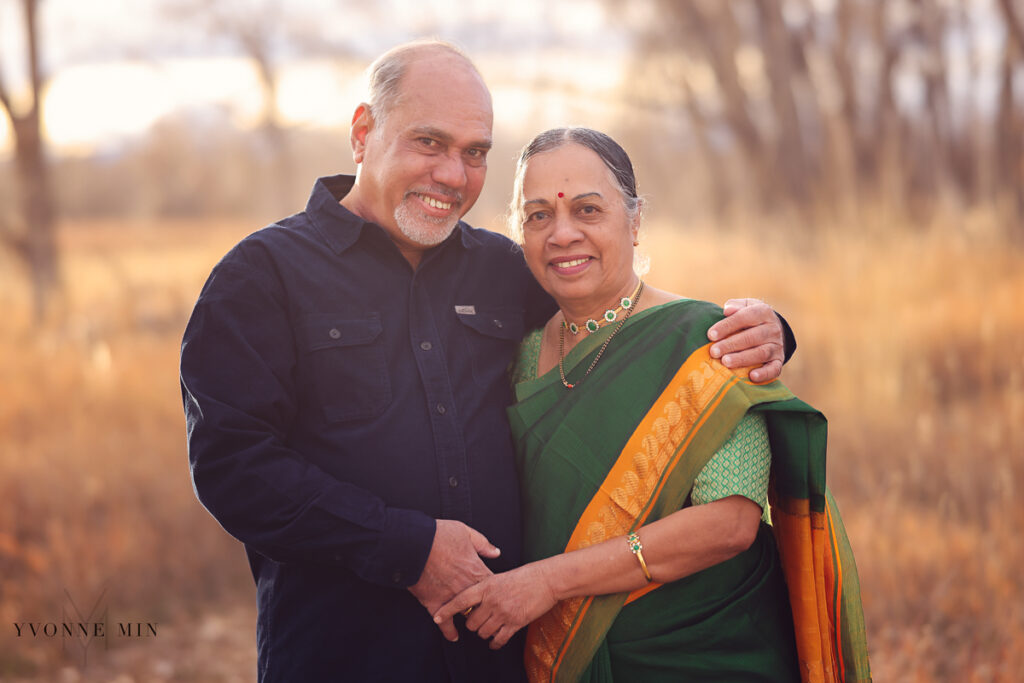 A grandmother and grandfather hug each other and look at the camera their family shoot with Yvonne Min Photography in Thornton, Colorado.