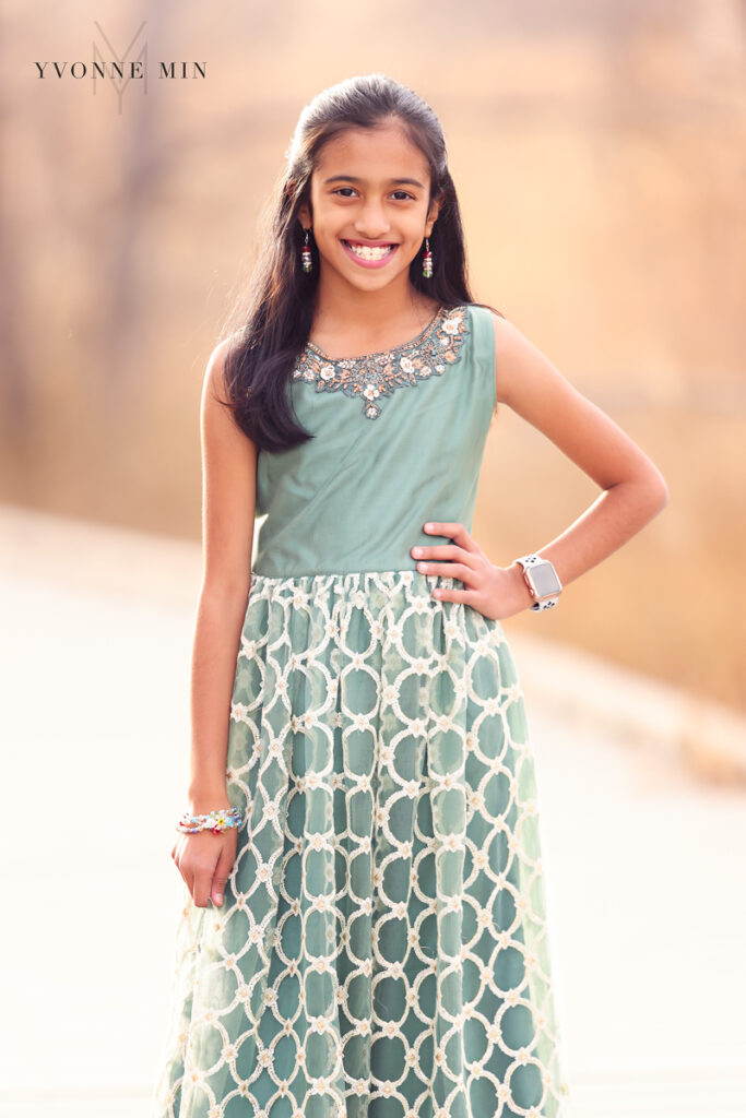 A young girl poses in a traditional Indian saree on a bridge at sunset at a family photoshoot with Yvonne Min Photography.