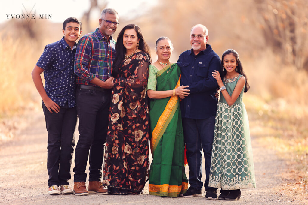 A family with six members stands together on a trail in Thornton, Colorado at their family photo session with Yvonne Min Photography.