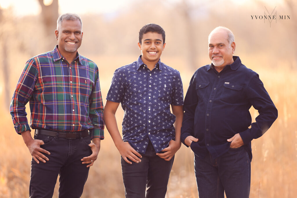 A grandson, father and grandfather stand near each other and pose for the camera a family photoshoot in Thornton, Colorado.