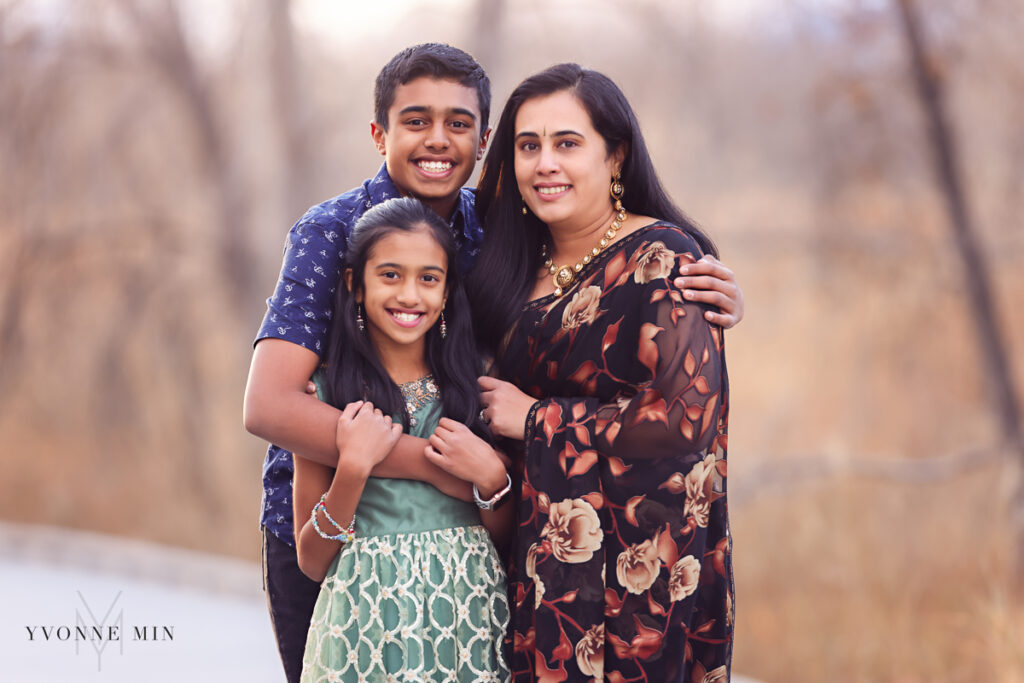 A mom, her son and her daughter hug together on a bridge at sunset in Thornton, Colorado during a family photoshoot session.