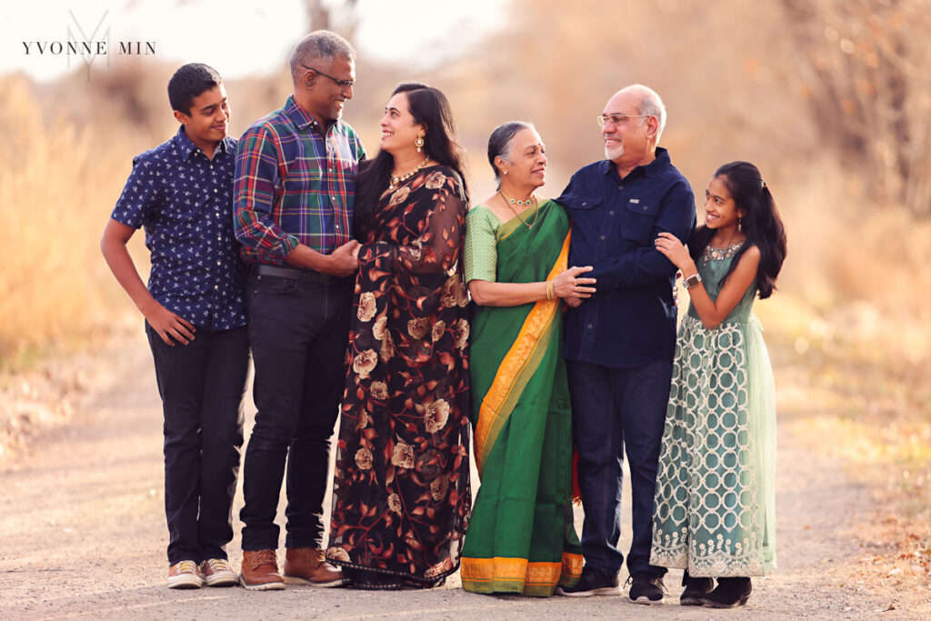 A family with six members stands together on a trail in Thornton, Colorado at their family photo session with Yvonne Min Photography.