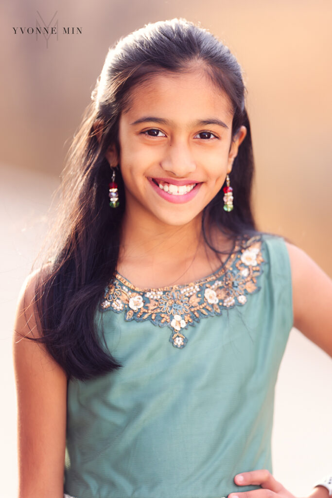 Young Indian woman in a green saree poses for the camera.