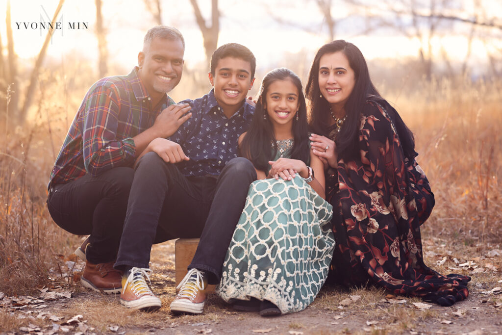 A family of four cuddle up together at sunset during a photoshoot with Yvonne Min Photography.