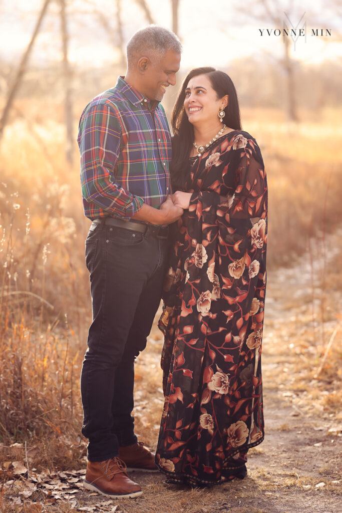 A mom and dad hug each other with the mom wearing a traditional saree at a family photoshoot.