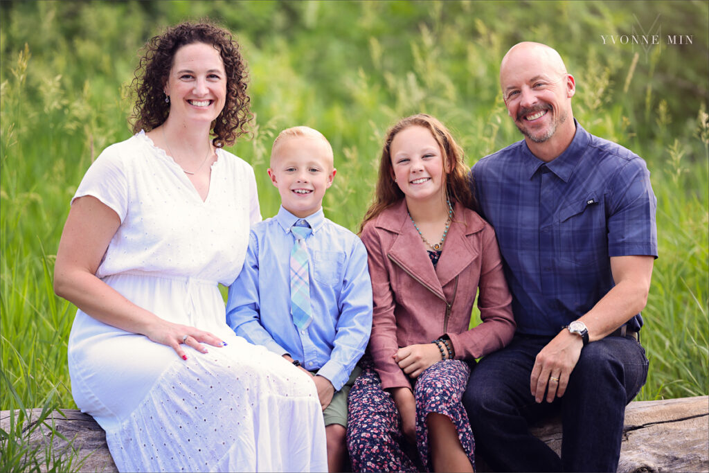 A photograph of a family sitting on a log together taken at McKay Lake in Westminster, Colorado by Yvonne Min Photography.