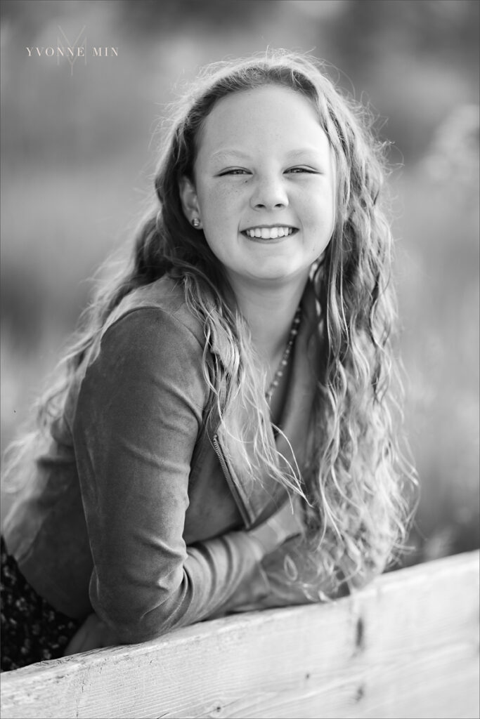A black and white photograph of a young girl posing at McKay Lake during her family photoshoot with Yvonne Min Photography in Westminster, Colorado.