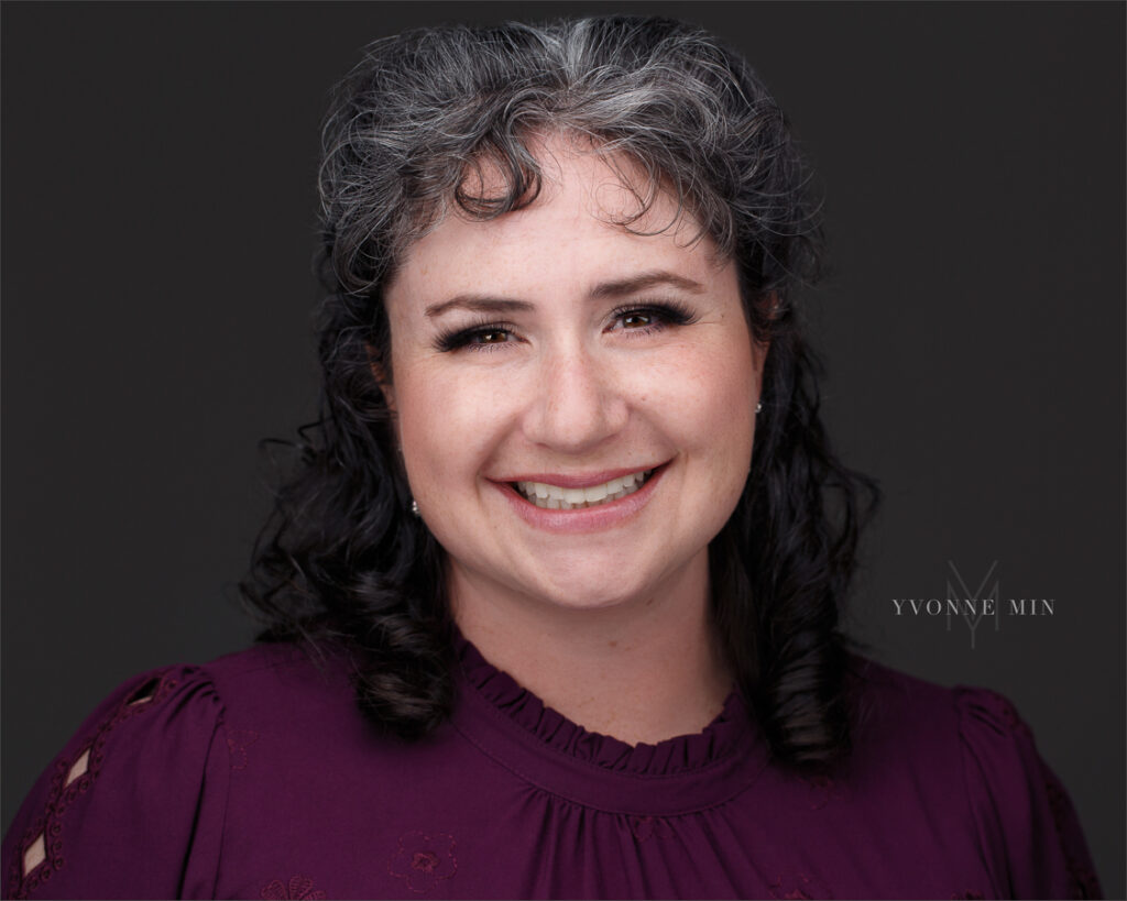 A headshot of a business woman against a dark gray backdrop in the studio of Yvonne Min Photography I. Thornton, Colorado.