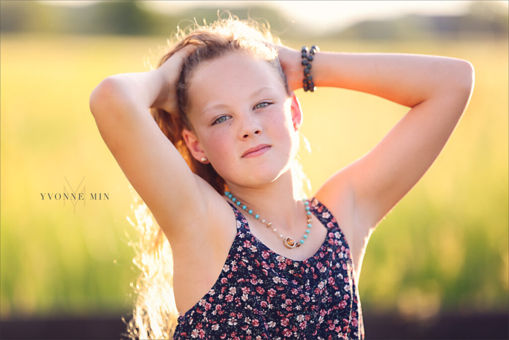 A photograph of a young girl pulling her hair back at her family photo session with Yvonne Min Photography at McKay Lake.