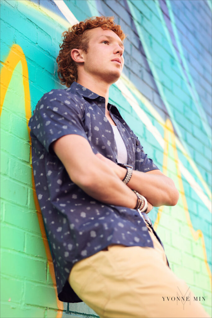 A high school senior poses in front of a colorful mural in the RiNo Art District of Denver with Yvonne Min Photography.