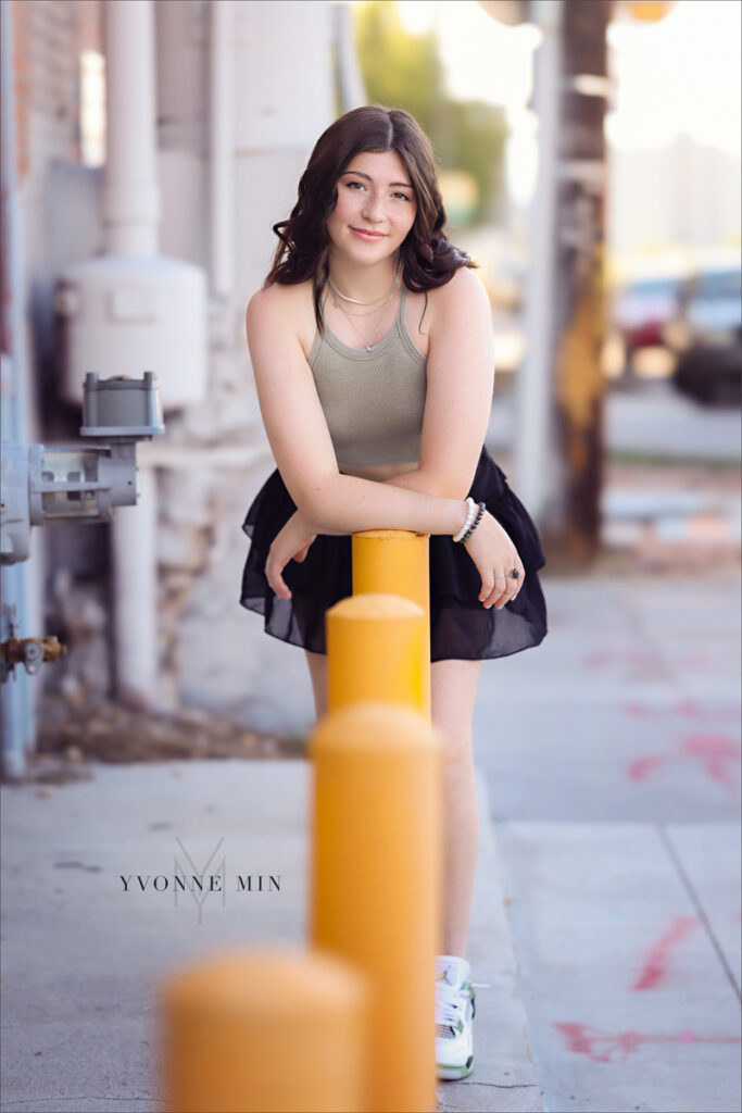 A high school senior poses in front of a colorful mural in the RiNo Art District of Denver with Yvonne Min Photography.