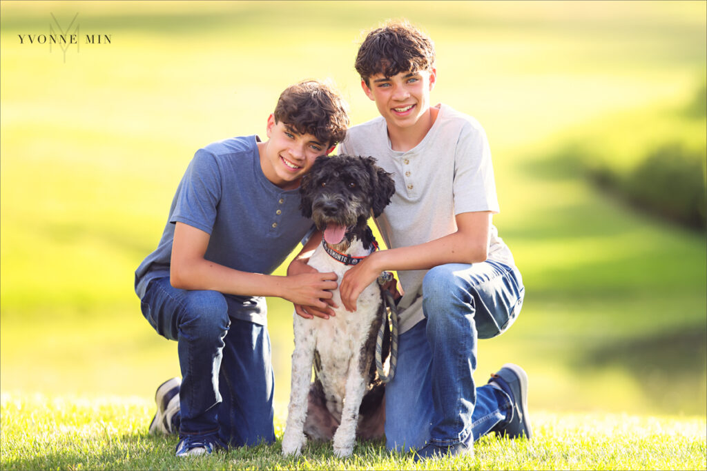 Two twin teenage brothers pose together with their dog at their family photography session with Yvonne Min Photography at Purple Park, Superior, Colorado.