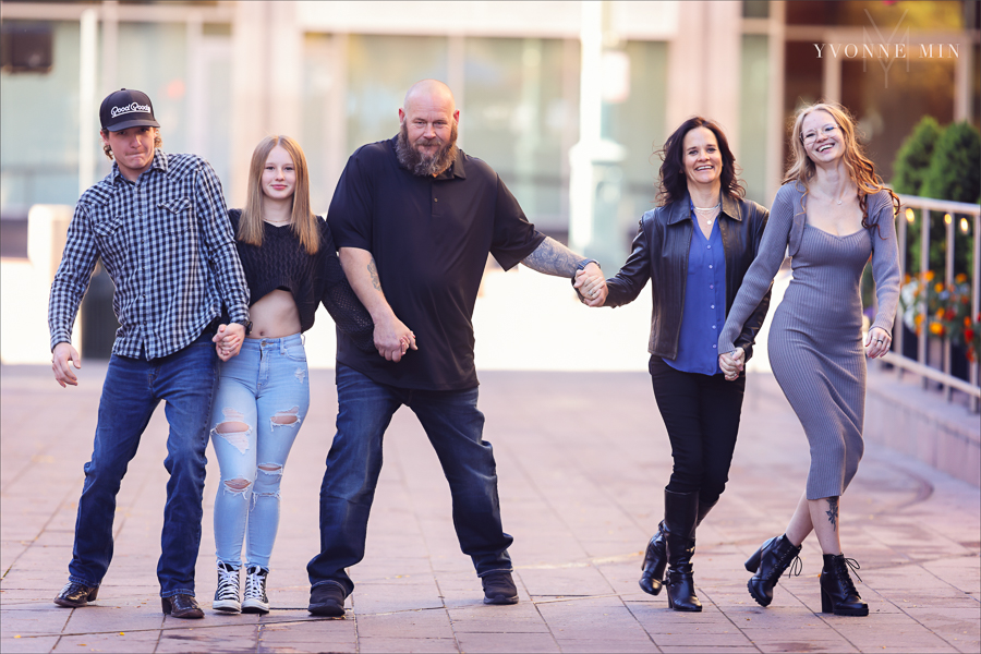 A family of five laugh as they walk in front of the Union Station sign during their family session with Yvonne Min Photography in downtown Denver.