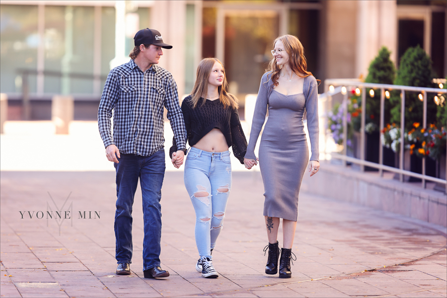 Three adult siblings walking together in front of Union Station during an Yvonne Min Photography family photo session in downtown Denver.