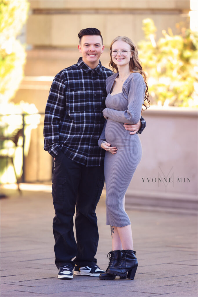 A photograph of an expecting mom and her husband taken outside Union Station in downtown Denver by Yvonne Min Photography.