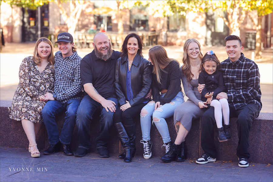 A family photograph with eight people sitting on a bench taken outside Union Station in downtown Denver by Yvonne Min Photography.