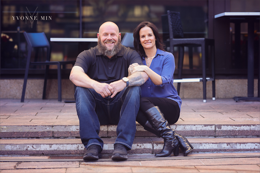 A mom and dad sitting on a sidewalk during their family photography session with Yvonne Min Photography outside Union Station in downtown Denver.