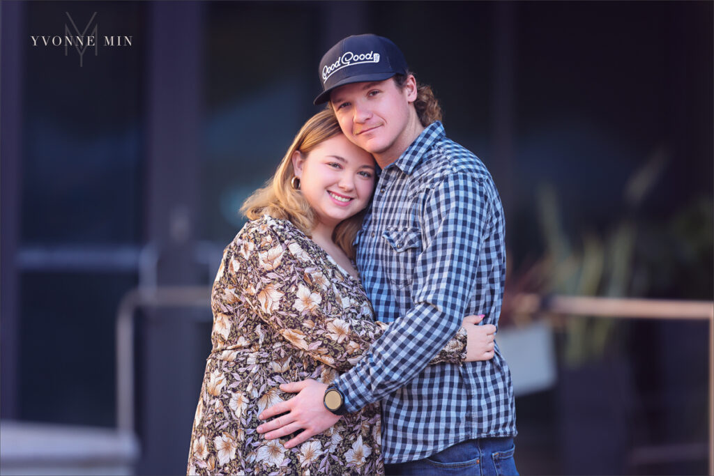 A young couple hugs each other outside Union Station in LoDo Denver during a family photography session with Yvonne Min Photography.