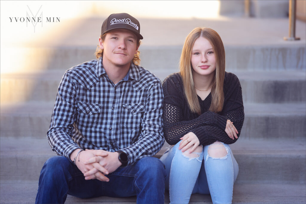 A brother and sister sit on the concrete steps outside Union Station in LoDo Denver during a family photography session with Yvonne Min Photography.