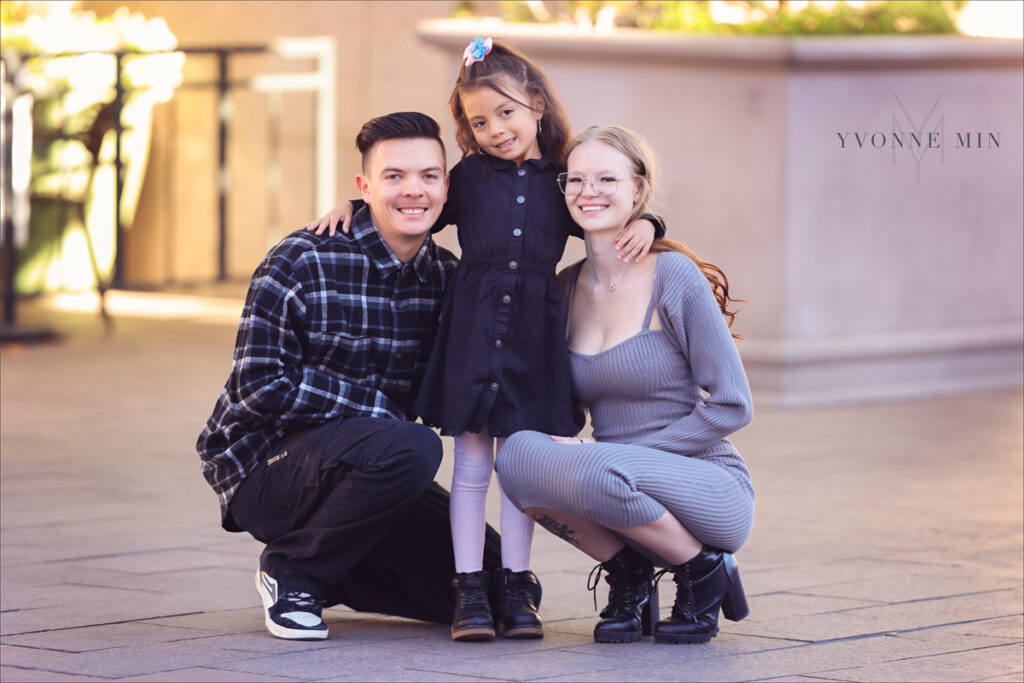 A photograph of an expecting mom and her husband holding their young daughter taken outside Union Station in downtown Denver by Yvonne Min Photography.