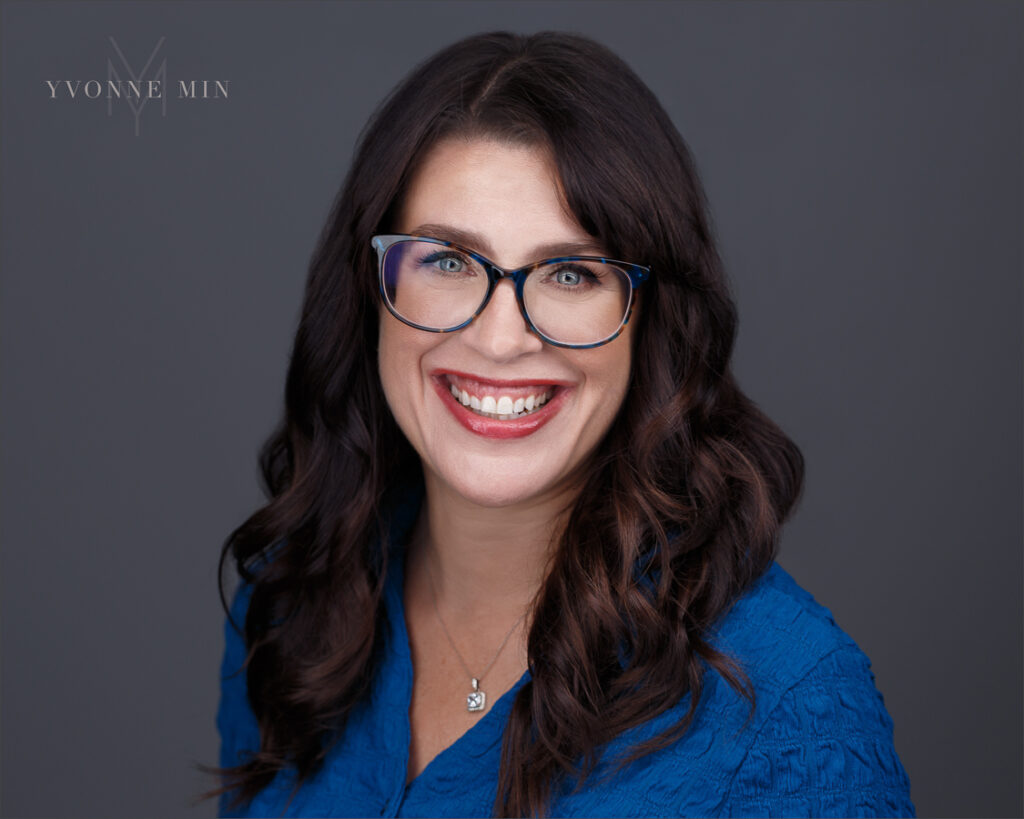 A new headshot of a Boulder therapist wearing a blue shirt on a dark gray background taken by Yvonne Min Photography in Thornton, Colorado.
