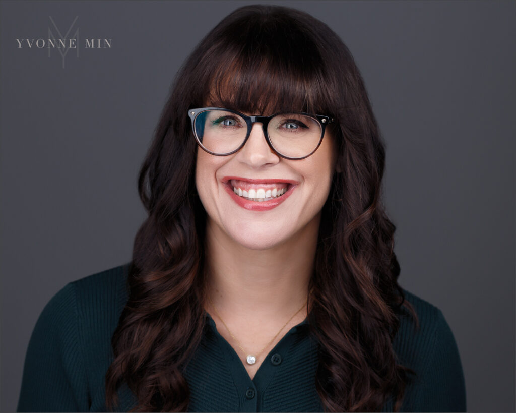 A new headshot of a Boulder therapist wearing a dark green shirt and glasses on a dark gray background taken by Yvonne Min Photography in Thornton, Colorado.