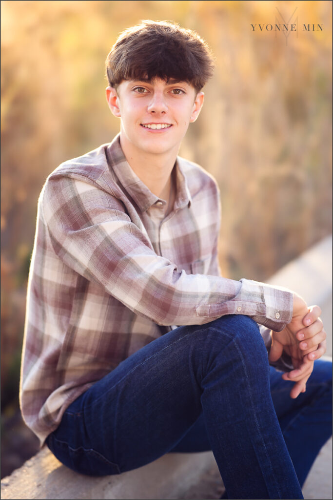 A teen boy sits on a small bridge during a family photoshoot session with Yvonne Min Photography in Thornton, Colorado.