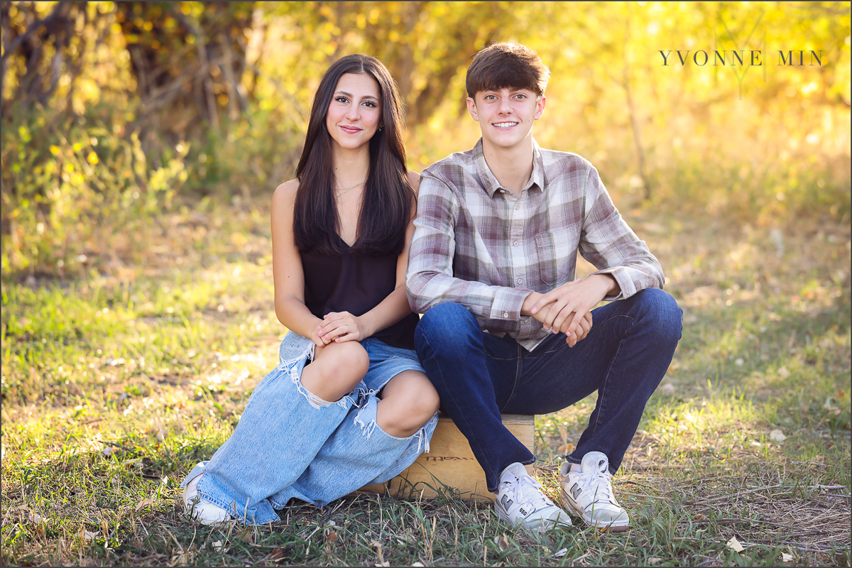 A brother and sister sit on an apple box together during their family photoshoot with Yvonne Min Photography in Thornton, Colorado.