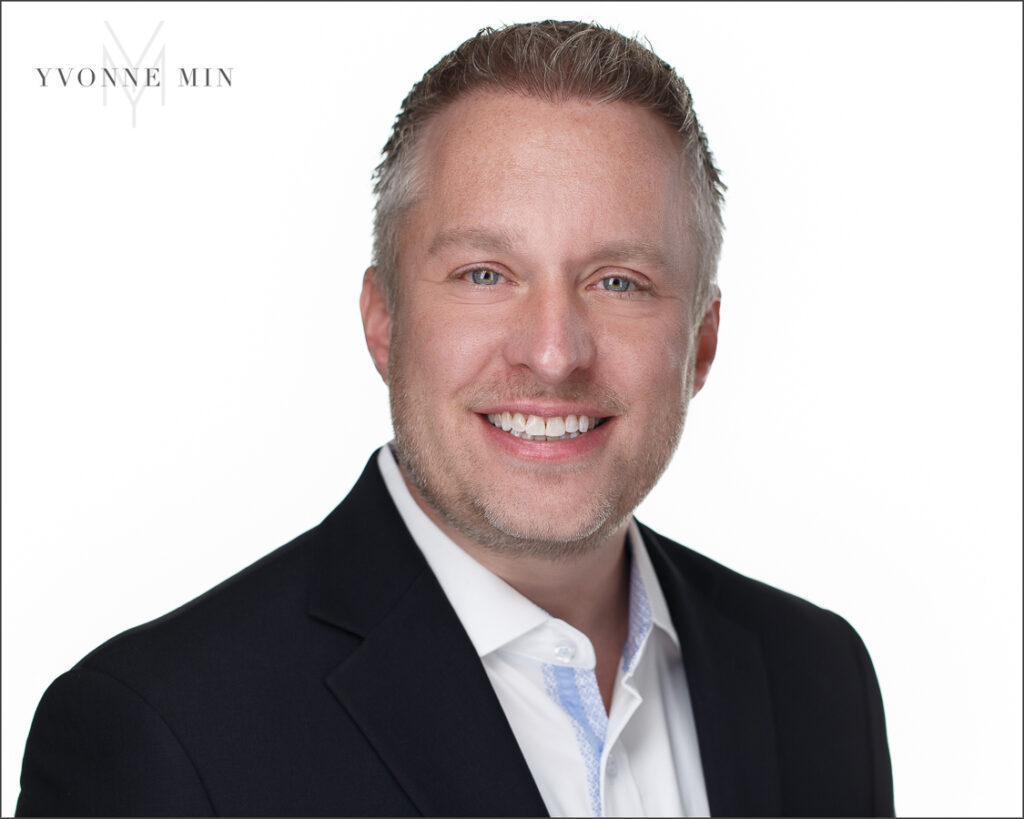 A new headshot for a man running for Thornton City Council photographed by Yvonne Min Photography on a white backdrop at her studio in Thornton, Colorado.