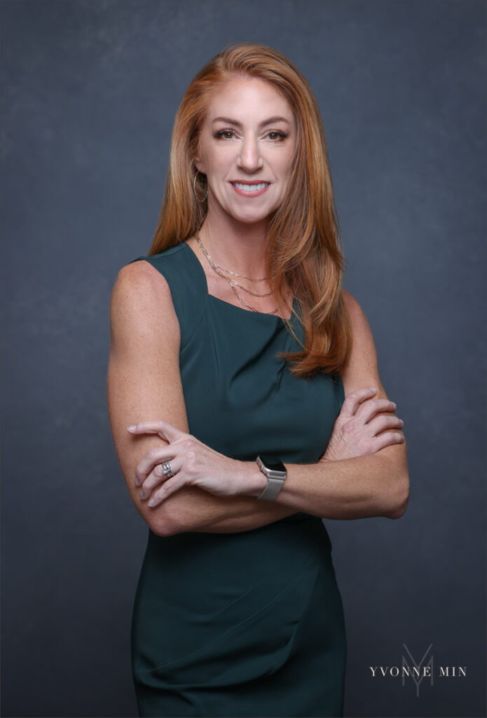 A corporate headshot of a professional woman photographed on a dark gray backdrop at the studio of Yvonne Min Photography in Thornton, Colorado.