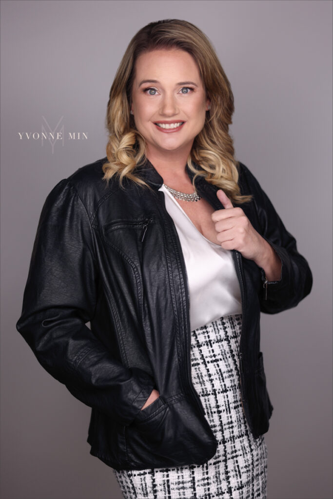A new professional headshot for a real estate agent photographed on a dark gray backdrop in the studio of Yvonne Min Photography in Thornton Colorado.