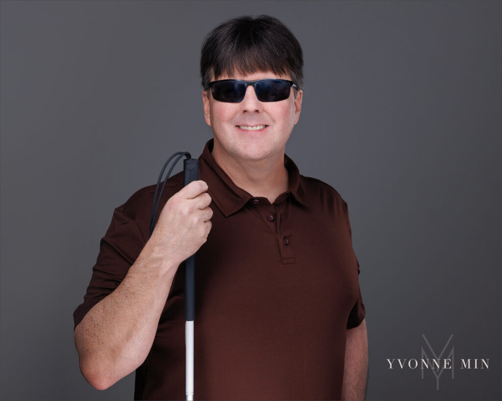 A  headshot of the founder of the Blind Institute of Technology taken at the Yvonne Min Photography Studio in Thornton, Colorado on a dark gray backdrop.