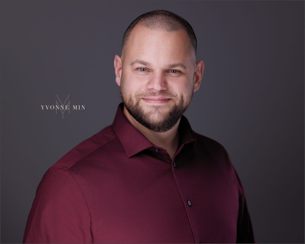 A new headshot for a business professional photographed on a dark gray background in the studio of Yvonne Min Photography in Thornton, Colorado.